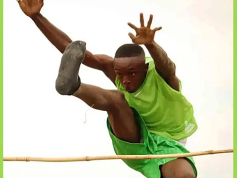 Athlete in green mid-air clearing a horizontal pole during a jump