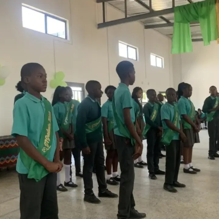 Students in green uniforms standing in rows inside a decorated hall
